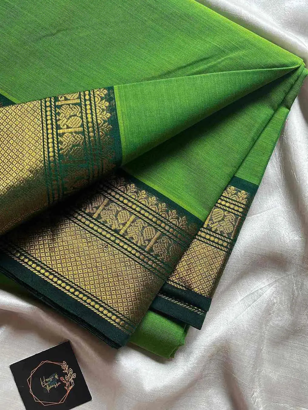 Green saree with gold border on a white background